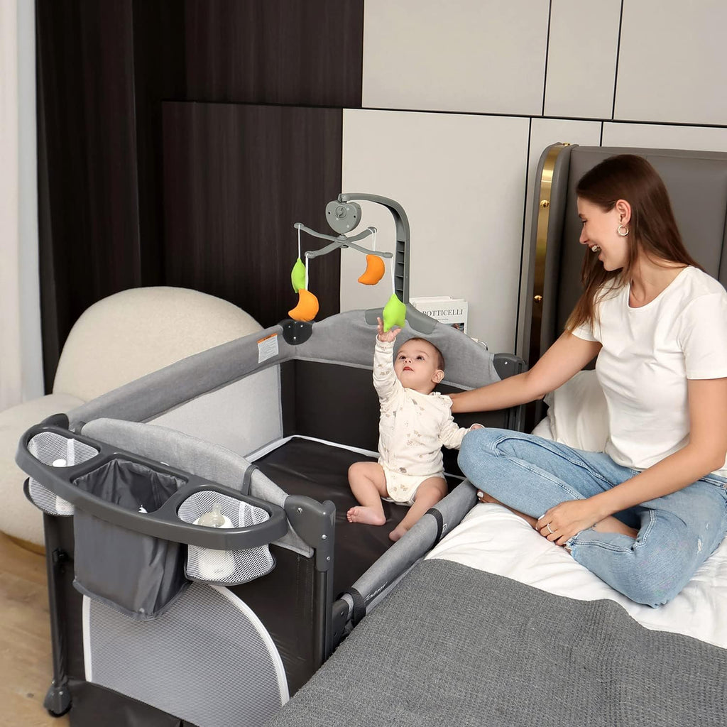 Zdolmy Baby Bedside Sleeper Bassinet, 4-in-1 Pack and Play with Bassinet w/Diaper Changing Table & Storage Bag, 3 Adjustable Heights, Toy Arch & Music, Portable Baby Play Yard with Carry Bag